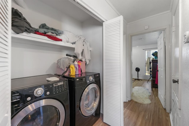 washroom with crown molding, baseboards, washing machine and dryer, laundry area, and wood finished floors