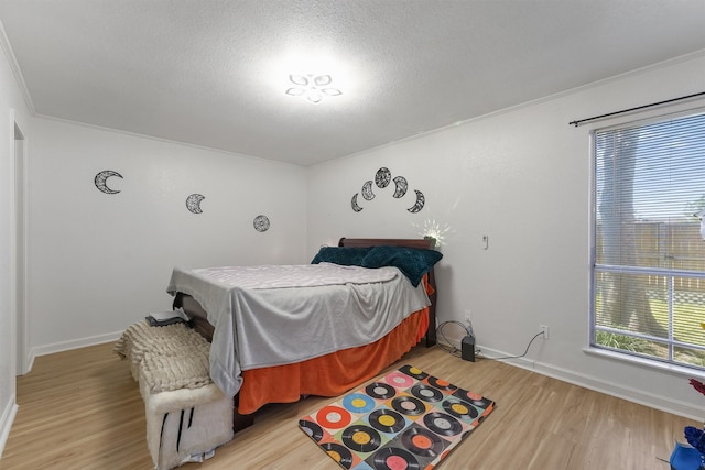 bedroom featuring wood finished floors, baseboards, and a textured ceiling