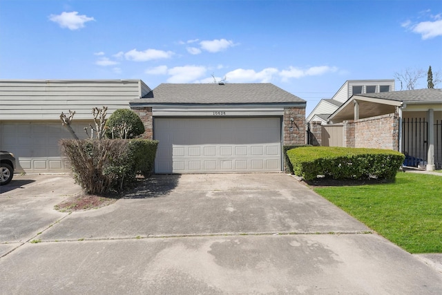 exterior space with a shingled roof, concrete driveway, a front lawn, and fence