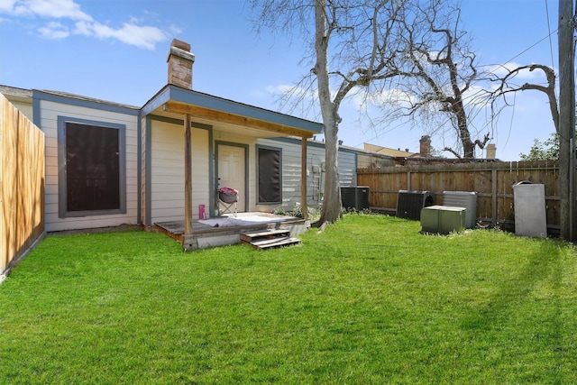 back of house featuring a lawn, cooling unit, a chimney, and a fenced backyard