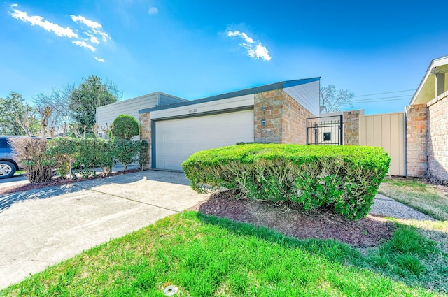 view of side of home featuring driveway, stone siding, and an attached garage