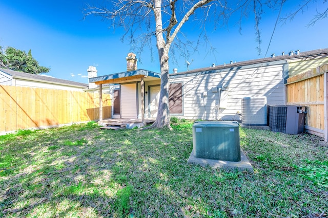 back of house with fence, central AC unit, and a lawn