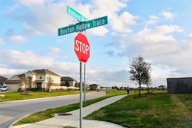 view of road featuring street lights, a residential view, curbs, sidewalks, and traffic signs