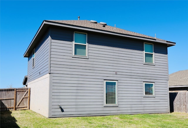 rear view of property featuring a lawn, brick siding, and fence