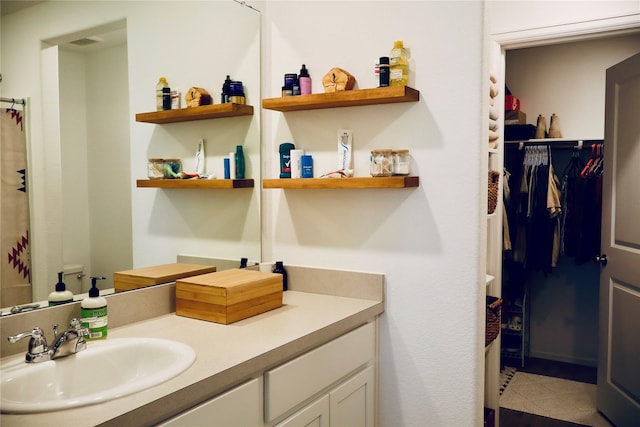 full bath featuring vanity, a walk in closet, and tile patterned flooring