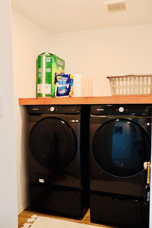 laundry room featuring visible vents, baseboards, washer and clothes dryer, laundry area, and light wood-style flooring