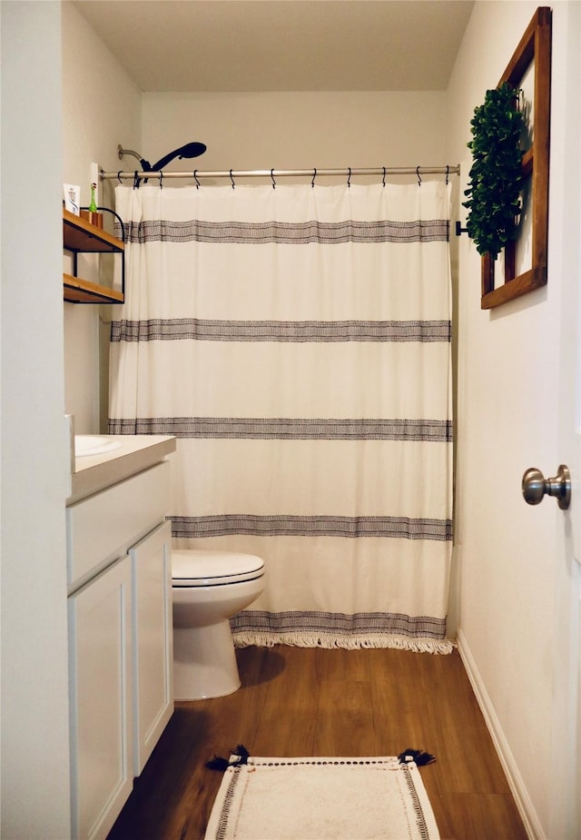 bathroom featuring curtained shower, baseboards, toilet, wood finished floors, and vanity