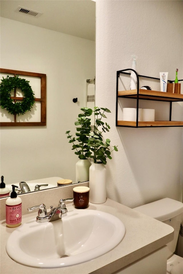 bathroom with visible vents, toilet, and vanity