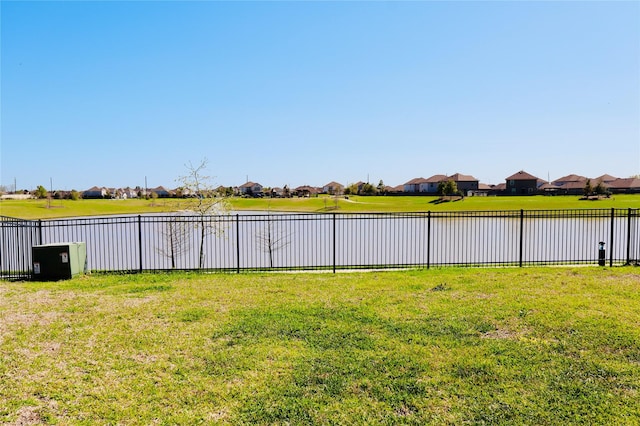 view of yard with fence, a residential view, and a water view