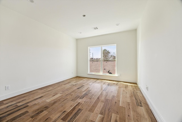 empty room with visible vents, baseboards, and wood finished floors