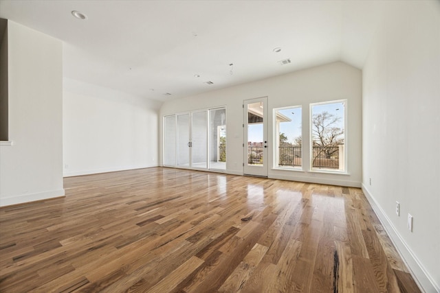 empty room with visible vents, baseboards, lofted ceiling, recessed lighting, and wood finished floors