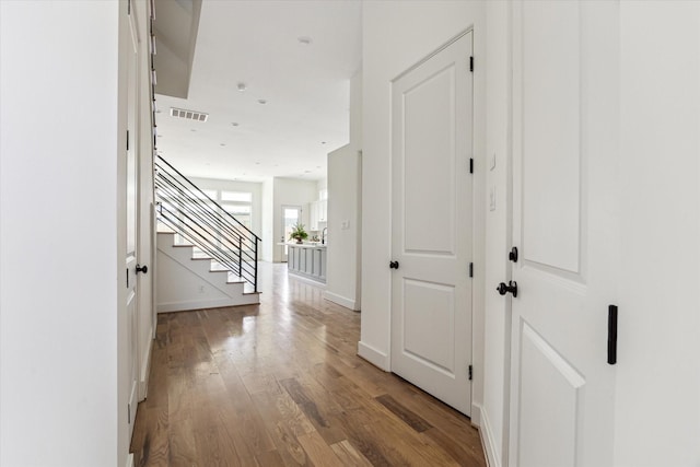 corridor with visible vents, baseboards, wood finished floors, and stairs