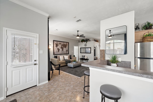 kitchen with visible vents, a ceiling fan, freestanding refrigerator, a breakfast bar area, and light tile patterned floors