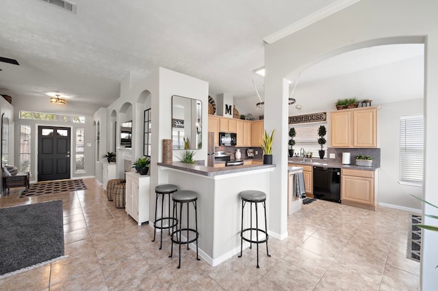 kitchen with a breakfast bar area, a sink, light brown cabinetry, black appliances, and backsplash