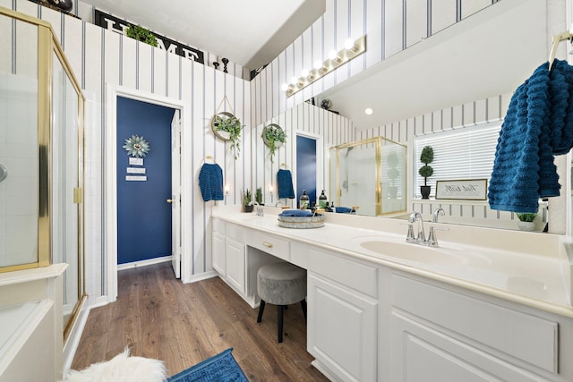 bathroom featuring a stall shower, wood finished floors, baseboards, and a sink