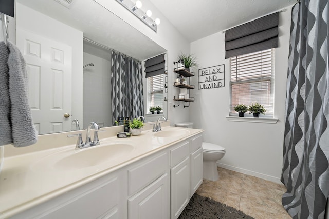 bathroom featuring a sink, baseboards, toilet, and double vanity