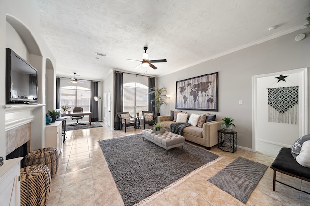 living room featuring visible vents, a ceiling fan, a textured ceiling, a fireplace, and baseboards