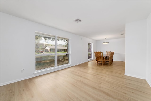 unfurnished dining area featuring light wood-style flooring, baseboards, and visible vents