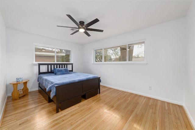 bedroom with light wood-type flooring, multiple windows, and baseboards