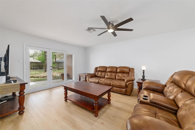 living room featuring crown molding, a ceiling fan, visible vents, and light wood-type flooring