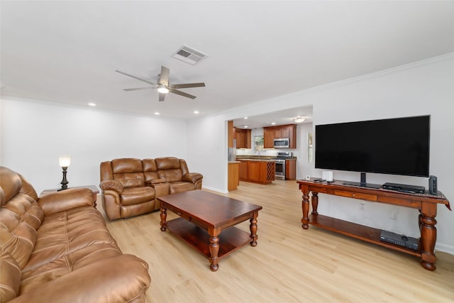 living room with a ceiling fan, visible vents, recessed lighting, ornamental molding, and light wood-style floors