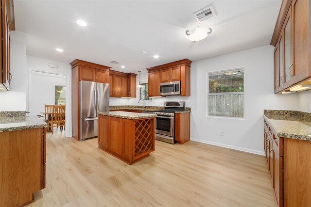 kitchen with visible vents, a kitchen island, baseboards, light wood-type flooring, and appliances with stainless steel finishes