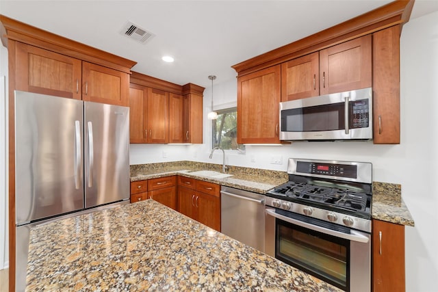 kitchen with brown cabinetry, visible vents, appliances with stainless steel finishes, and a sink