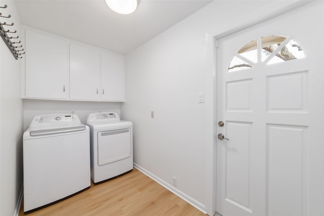 washroom featuring cabinet space, independent washer and dryer, light wood-style flooring, and baseboards