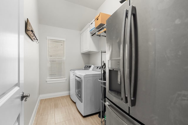 clothes washing area featuring separate washer and dryer, cabinet space, and baseboards