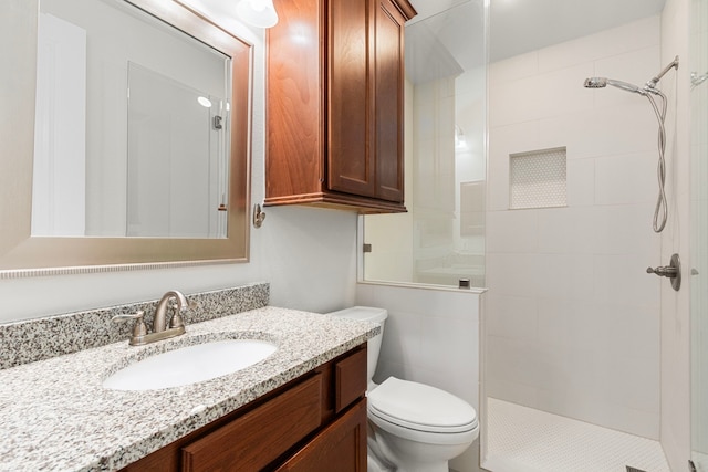 full bath featuring tiled shower, toilet, and vanity