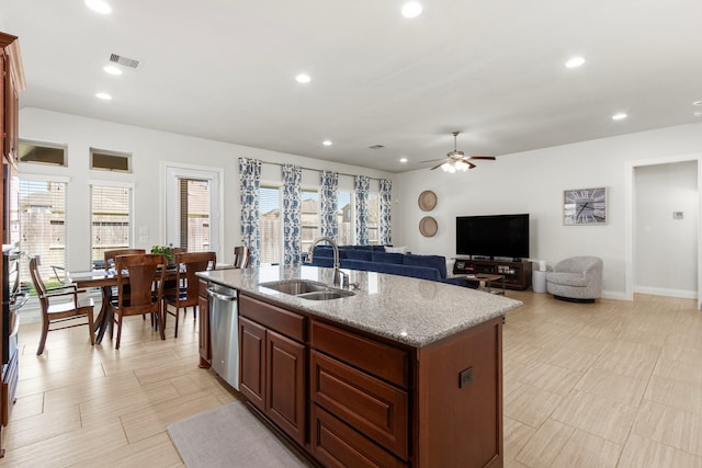 kitchen with visible vents, a sink, an island with sink, light stone counters, and stainless steel dishwasher