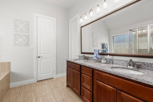 full bath featuring double vanity, baseboards, and a sink