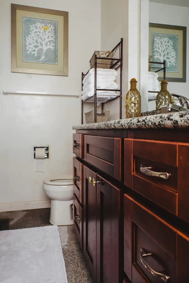 bathroom featuring baseboards, toilet, and vanity