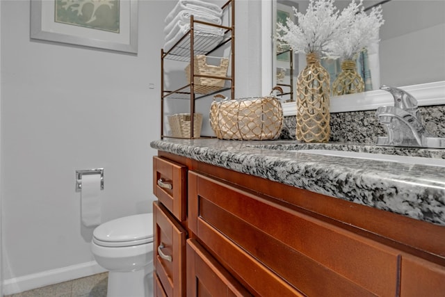 half bathroom featuring vanity, tile patterned floors, toilet, and baseboards