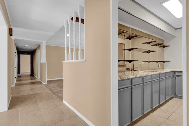 hallway with light tile patterned flooring, baseboards, and a sink