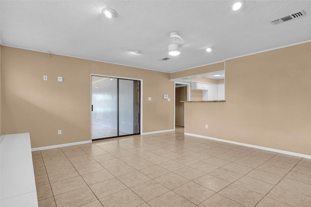 empty room with light tile patterned floors, visible vents, baseboards, and a textured ceiling