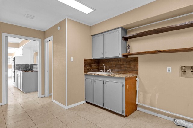 kitchen with a sink, decorative backsplash, open shelves, and gray cabinets