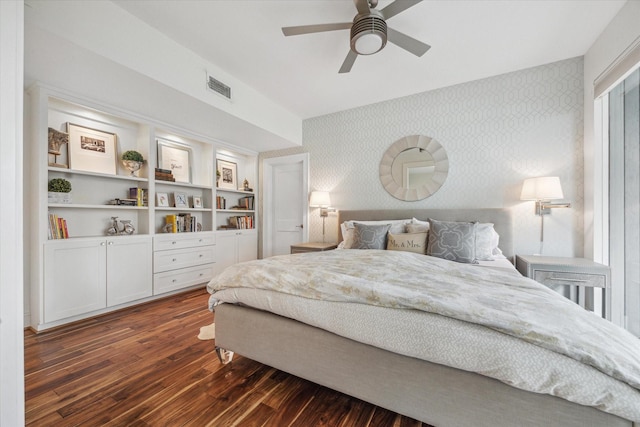 bedroom with wallpapered walls, visible vents, dark wood-style flooring, and ceiling fan