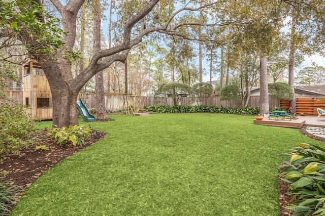 view of yard with a playground, a fenced backyard, and a wooden deck