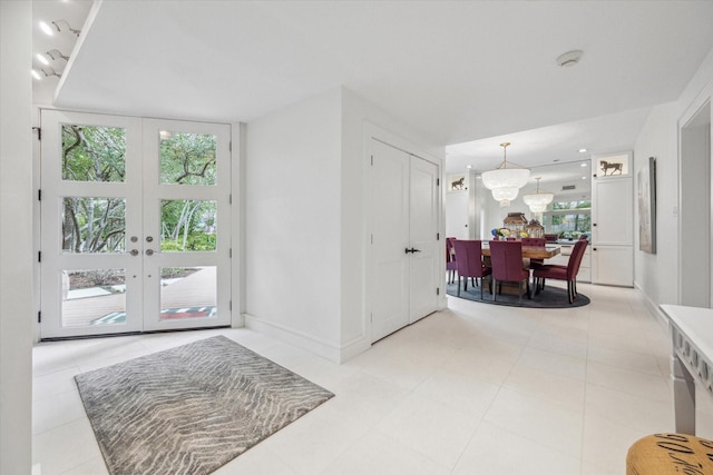 foyer entrance featuring an inviting chandelier, french doors, and baseboards