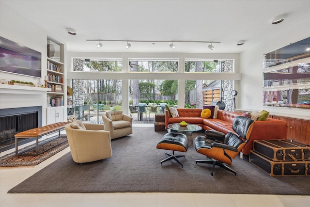 living room with plenty of natural light, built in shelves, a fireplace, and track lighting