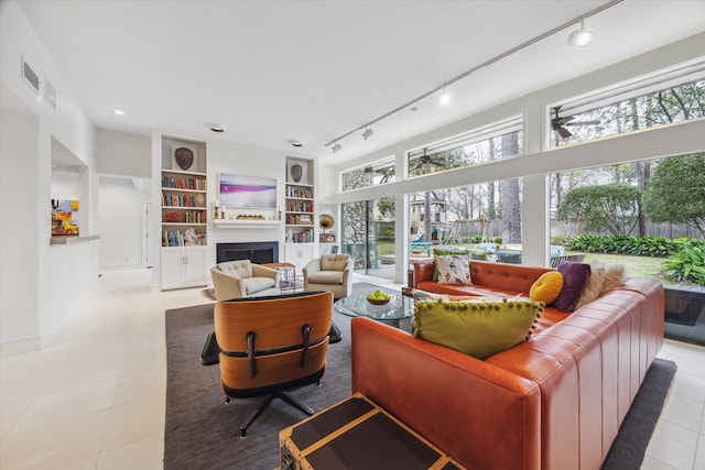 living room with visible vents, track lighting, built in features, light tile patterned flooring, and a fireplace