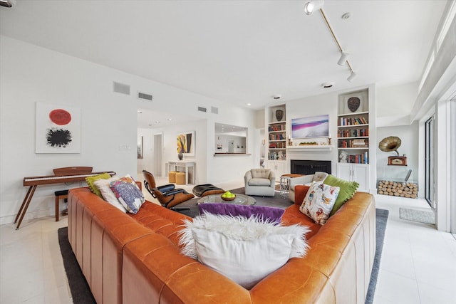 living room with built in shelves, light tile patterned floors, visible vents, a fireplace, and track lighting