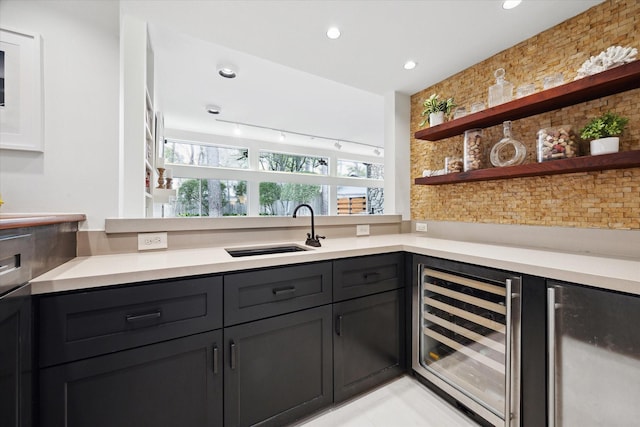 kitchen with wine cooler, open shelves, light countertops, and a sink