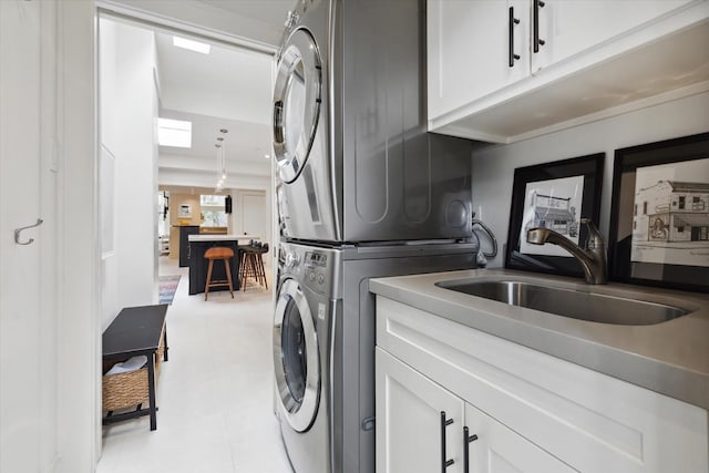 laundry room with cabinet space, stacked washer and clothes dryer, and a sink