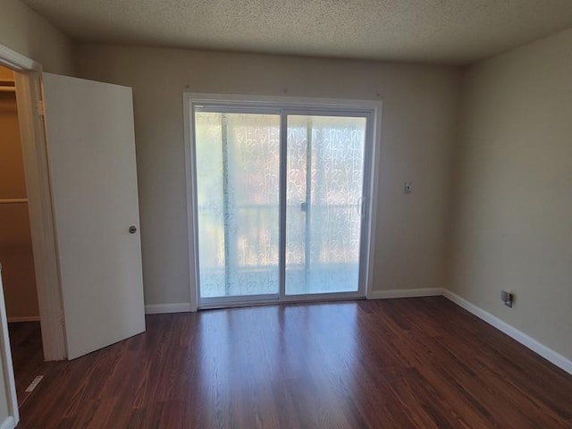 unfurnished room featuring wood finished floors, a healthy amount of sunlight, and a textured ceiling