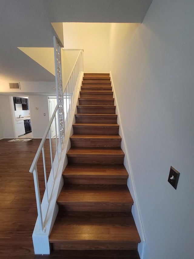 stairs with wood finished floors and visible vents