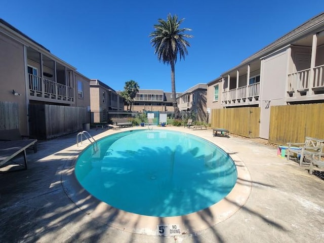 pool featuring a patio, fence, and a residential view