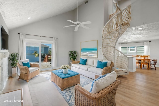 living area with high vaulted ceiling, visible vents, a textured ceiling, and wood finished floors