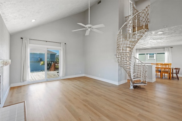 unfurnished living room with a ceiling fan, wood finished floors, baseboards, and a textured ceiling